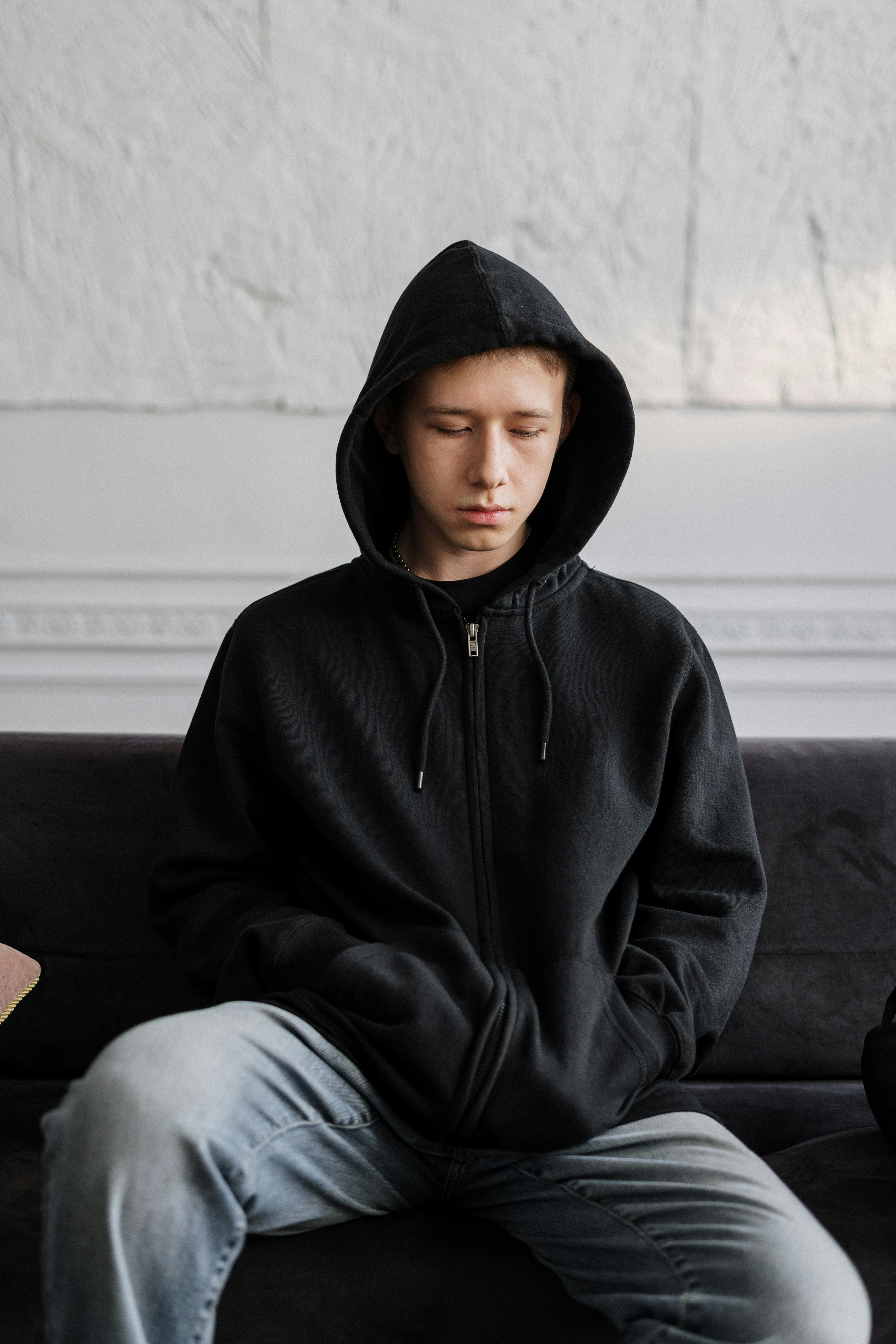 Young adult sitting thoughtfully in transitional housing setting